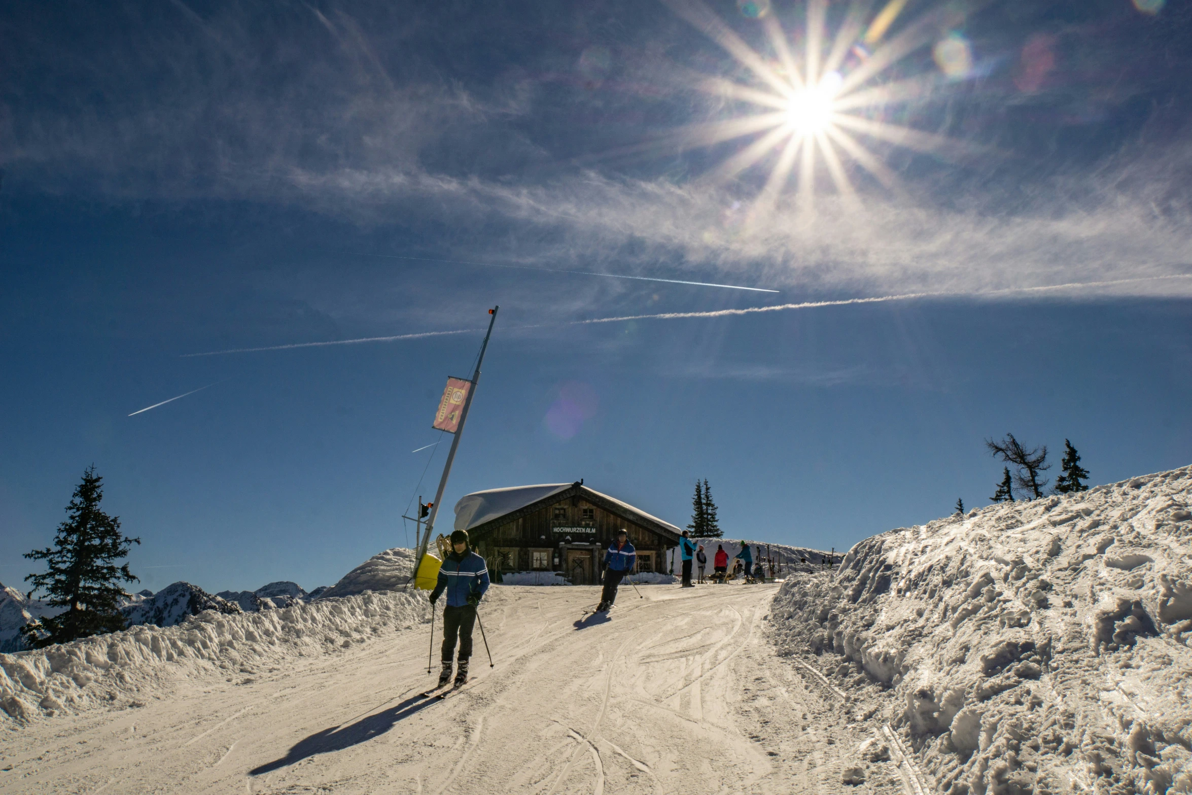 some skiers standing on a snowy path with a sign