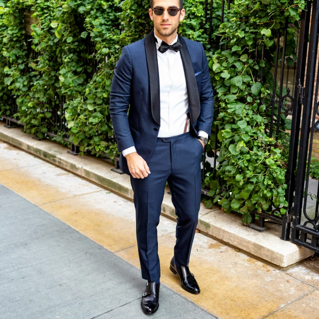 a man wearing a suit and sunglasses is standing outside