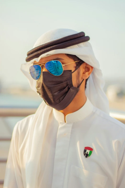 the man wears a mask and sunglasses while looking over his shoulder