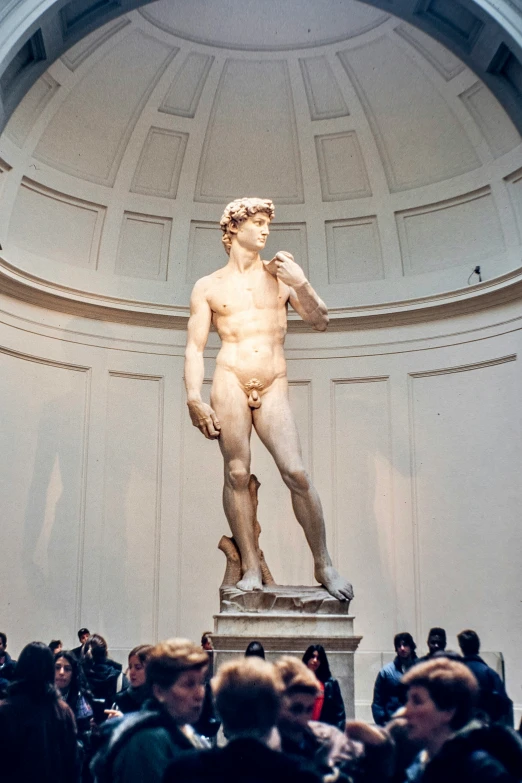 people gather to view a sculpture of a man standing on a pedestal