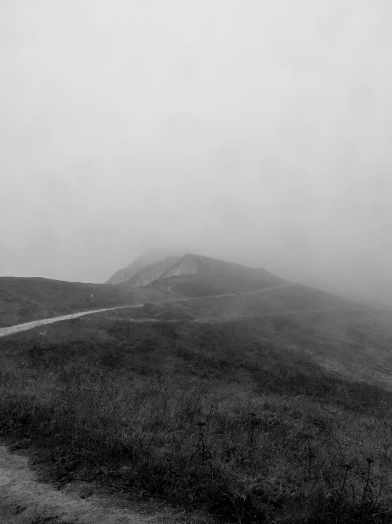 the road is going through the foggy hills