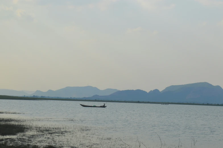 small boat floating in the middle of large lake