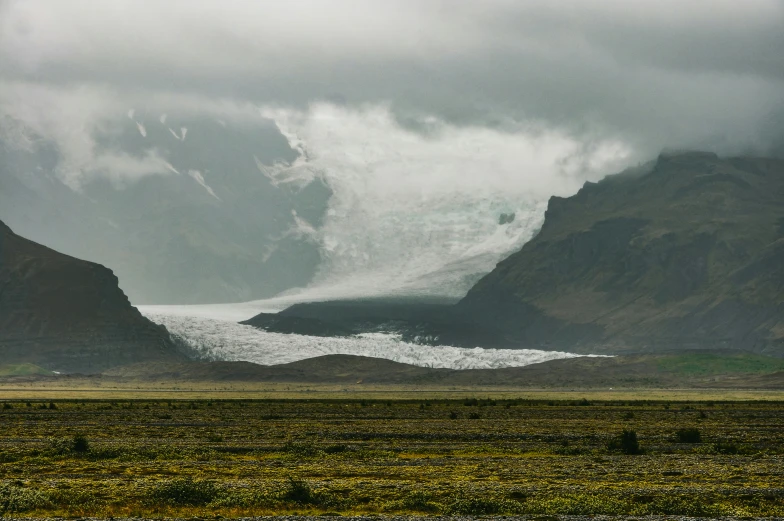 a glacier in the background with hills and a river behind