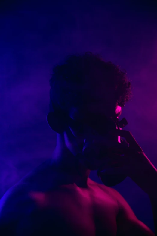 a man taking a phone call while silhouetted against purple lights