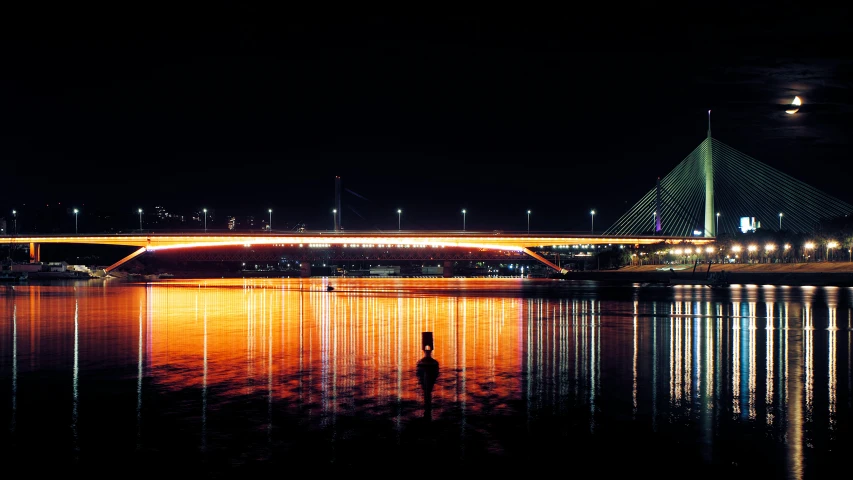 night scene of a bridge reflecting in the water with light streaks