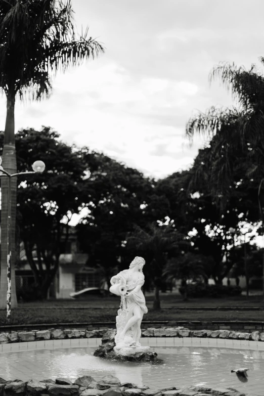 a white statue is standing in the middle of the park