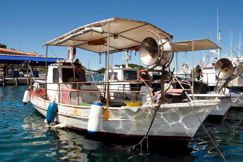 a white boat sitting at a dock with other boats nearby