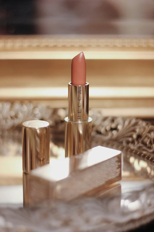 a pink lipstick sits on a table next to other items