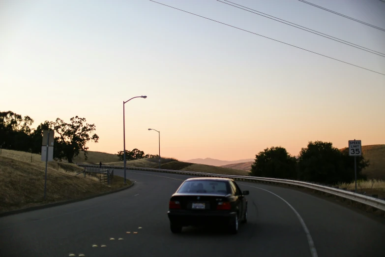 a car is parked in front of a speed limit sign on the side of the road