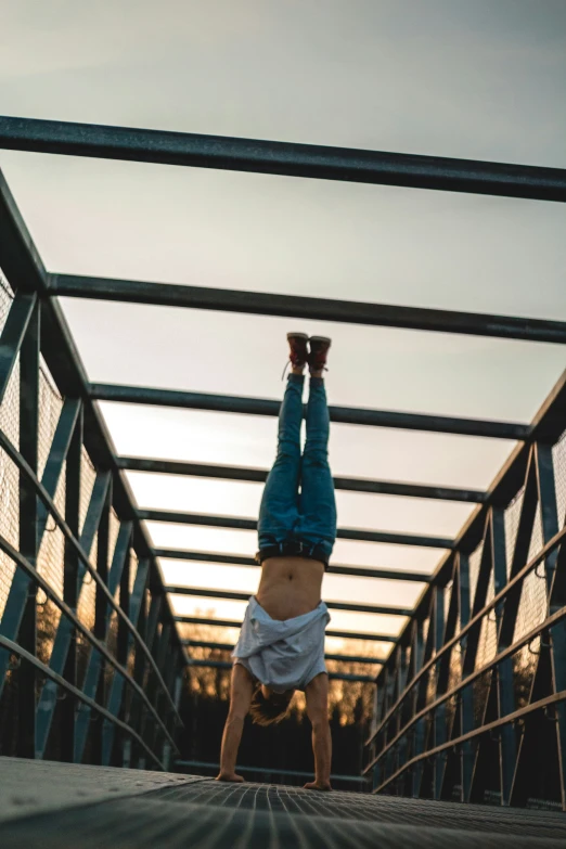 the person is doing a handstand on the bridge