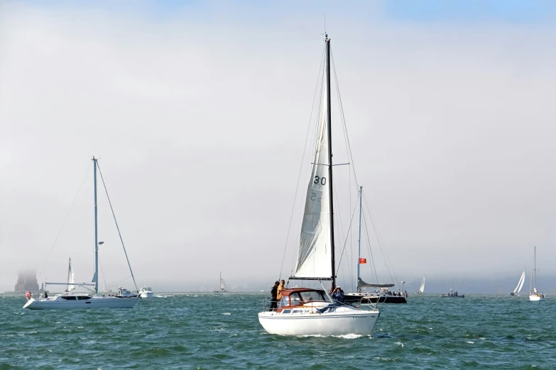 a white sailboat with four sails in blue water