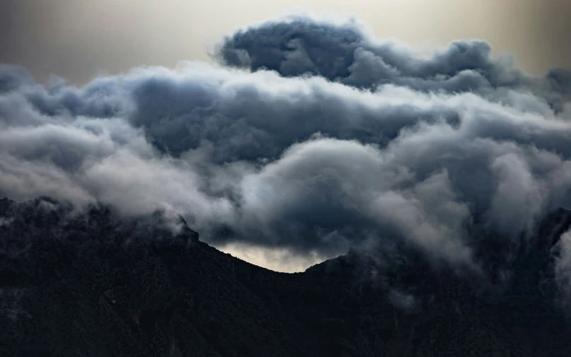 clouds over a mountain peak with a bird flying in it