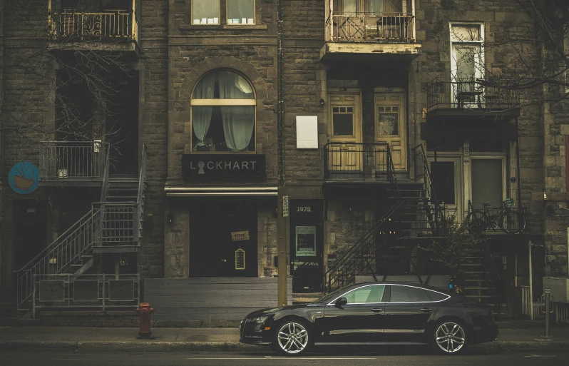 a car parked next to a tall building with stairs