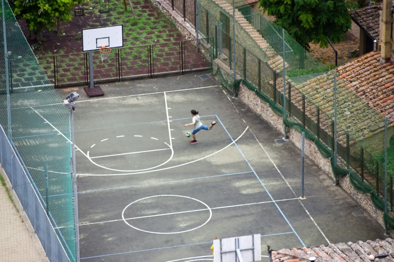 two people playing basketball on a court in a city