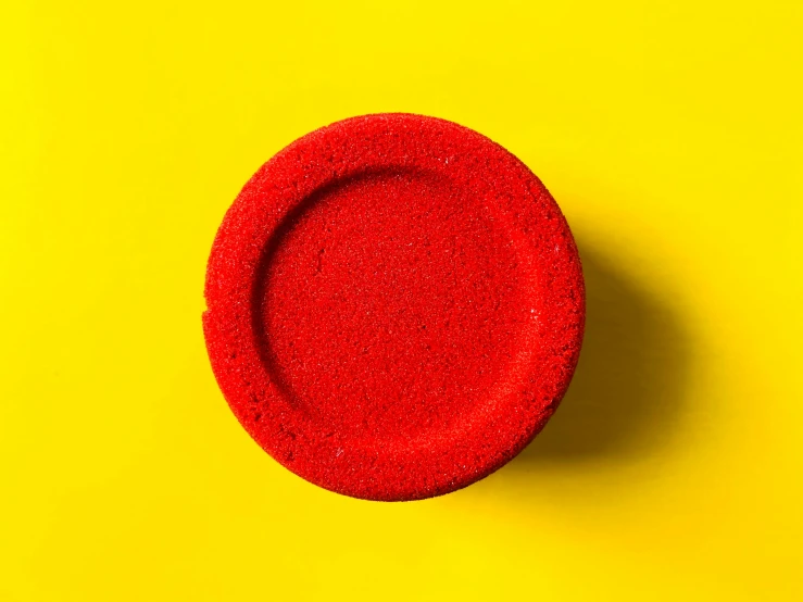 a red sponge is sitting on a yellow background