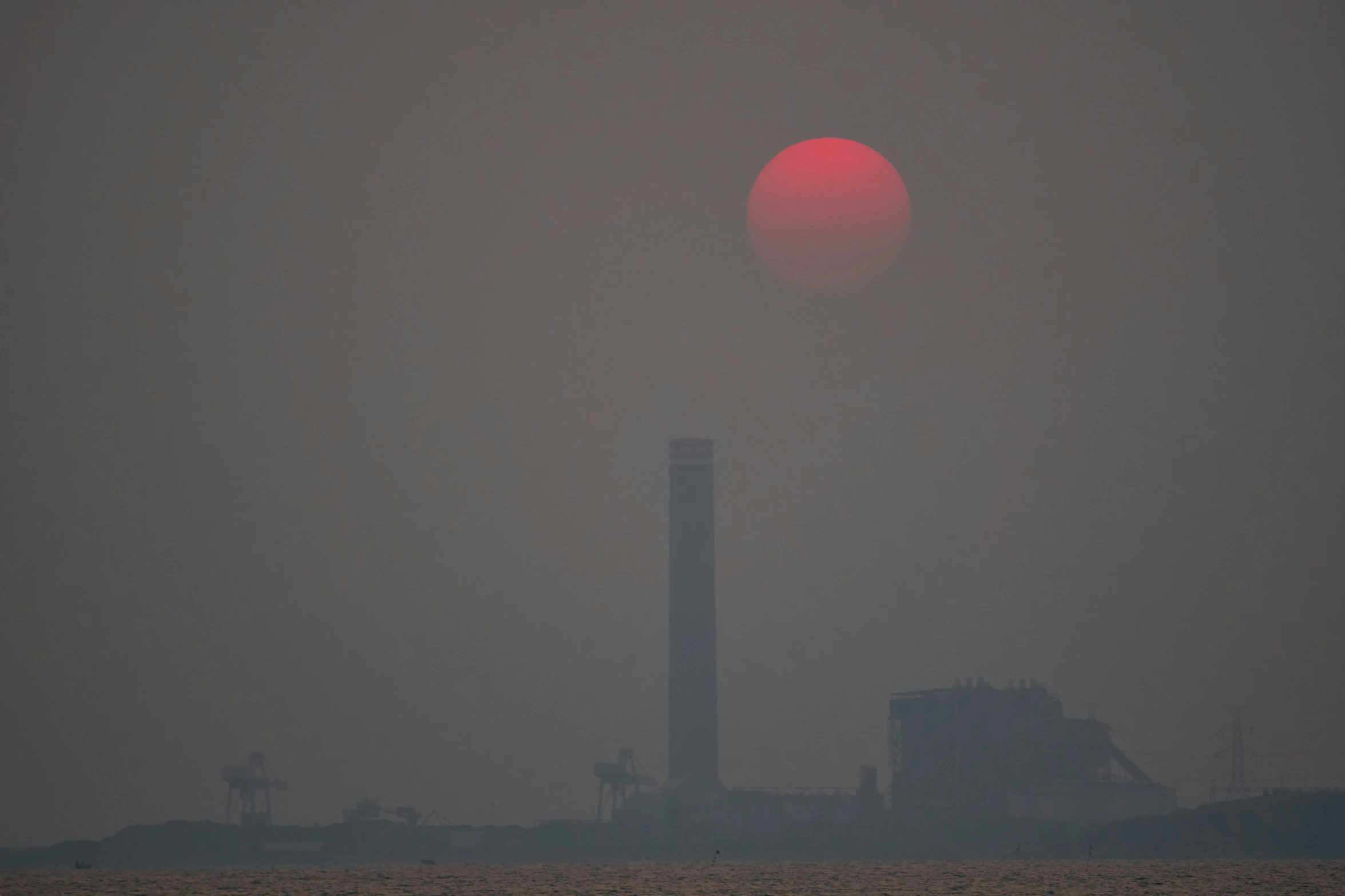 a foggy sunrise with a large red object in the distance