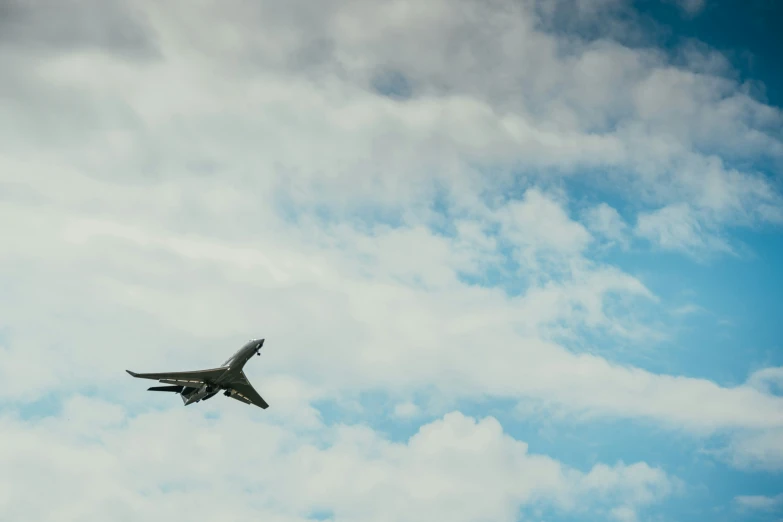 a jet flying across a cloudy sky with clouds