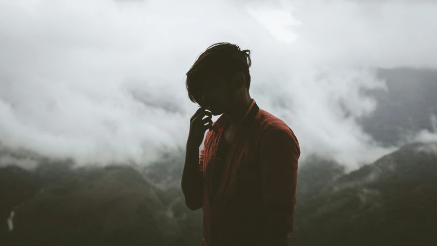 a person standing in the midst of clouds with their phone