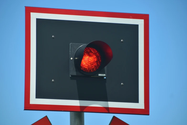 a traffic signal is lit red, in a blue sky