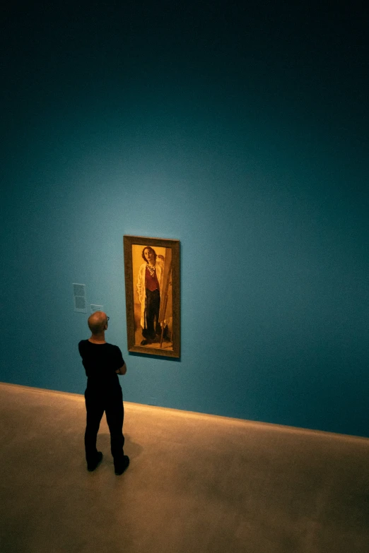 a man looking at a painting on a wall in an art museum