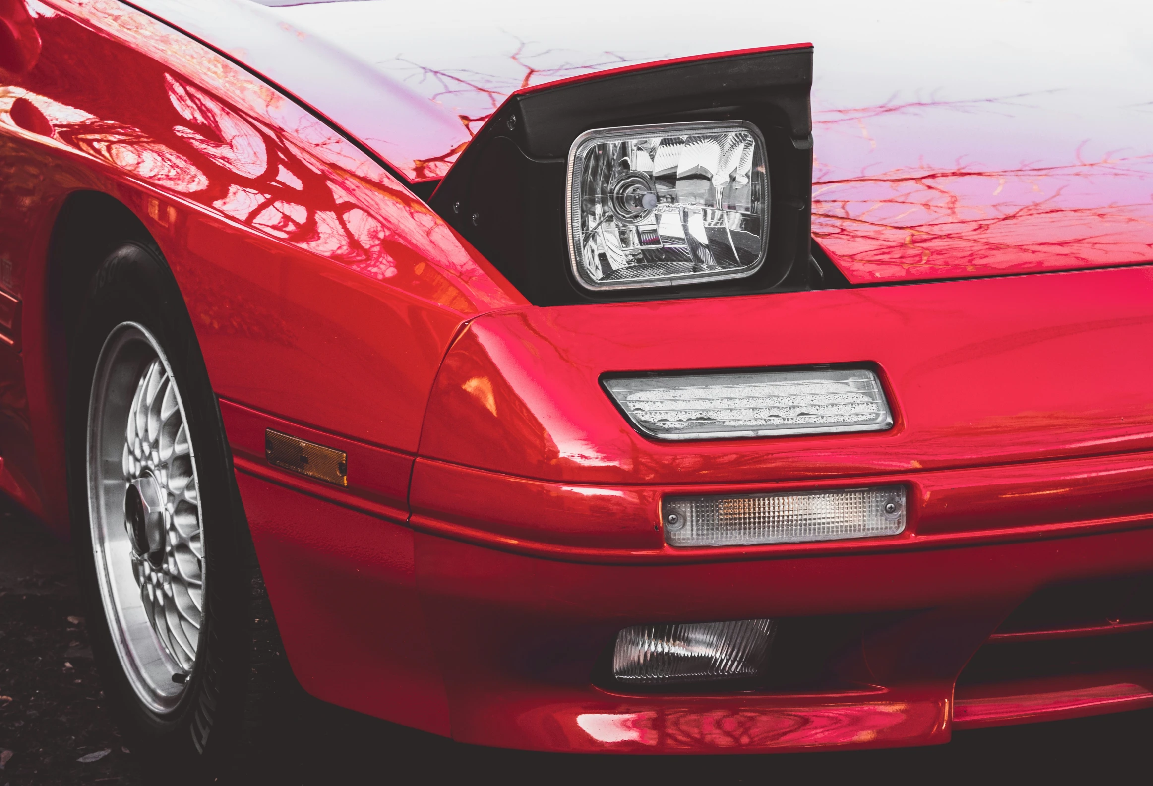 the front end of a red sports car with a black hood