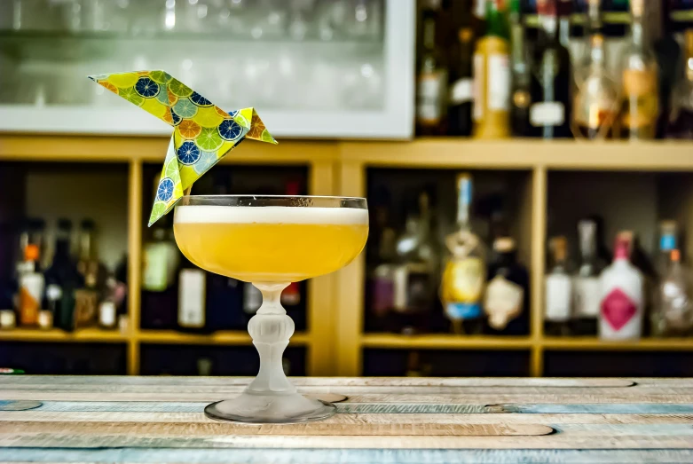 an upside down yellow drink is placed in a martini glass