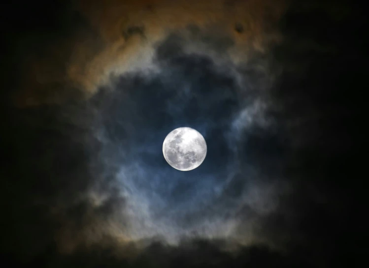 the moon is glowing behind a cloudy sky