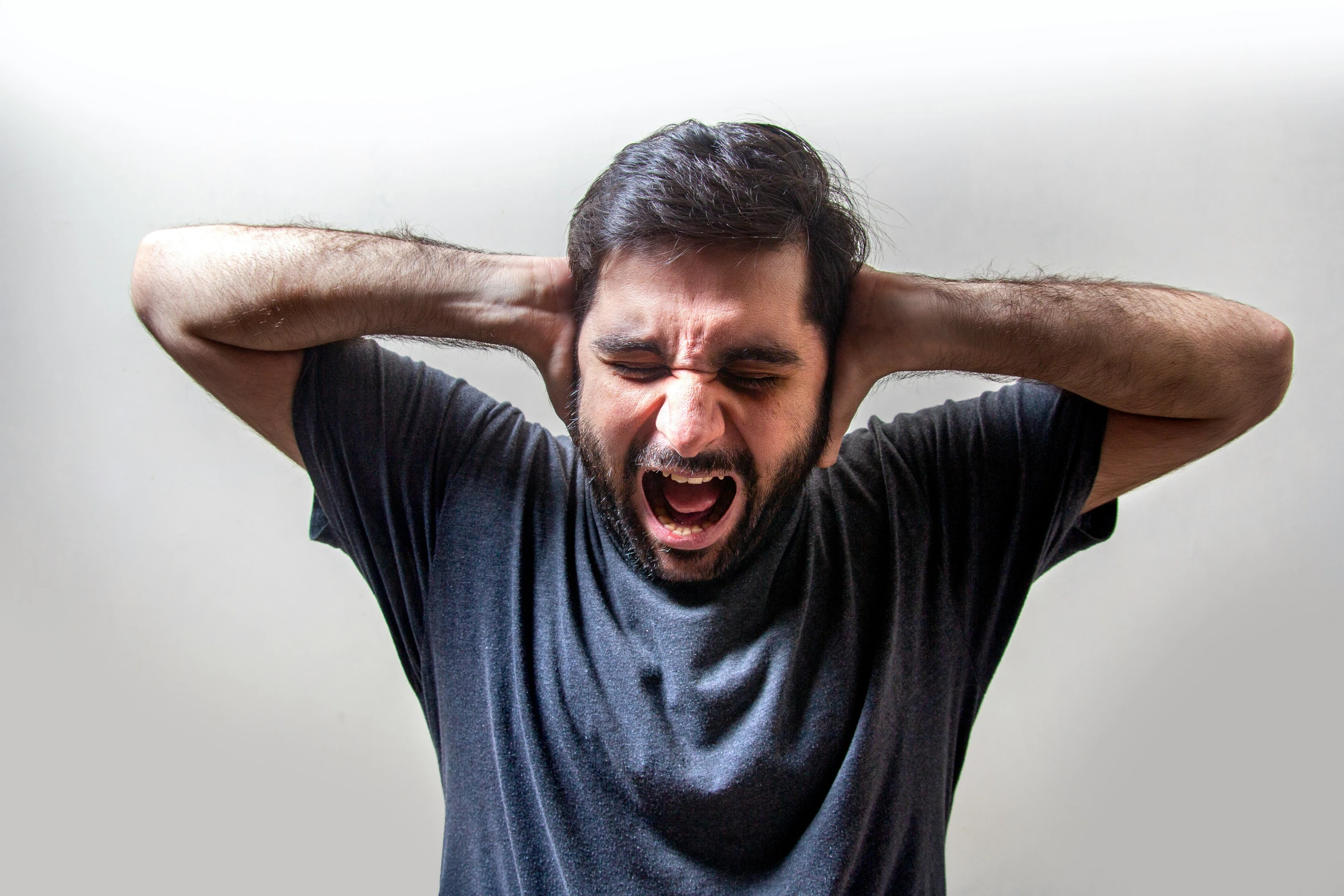 a man in a blue shirt with his hand on his head and fingers near his ears