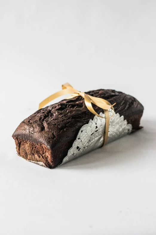 an edible chocolate pastry wrapped in ribbon on a white surface