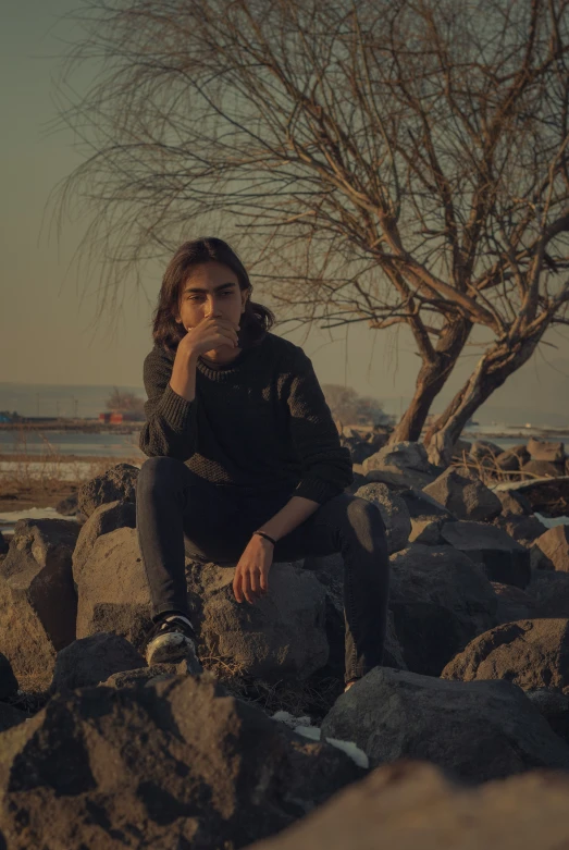 a man sitting on a rock next to a tree