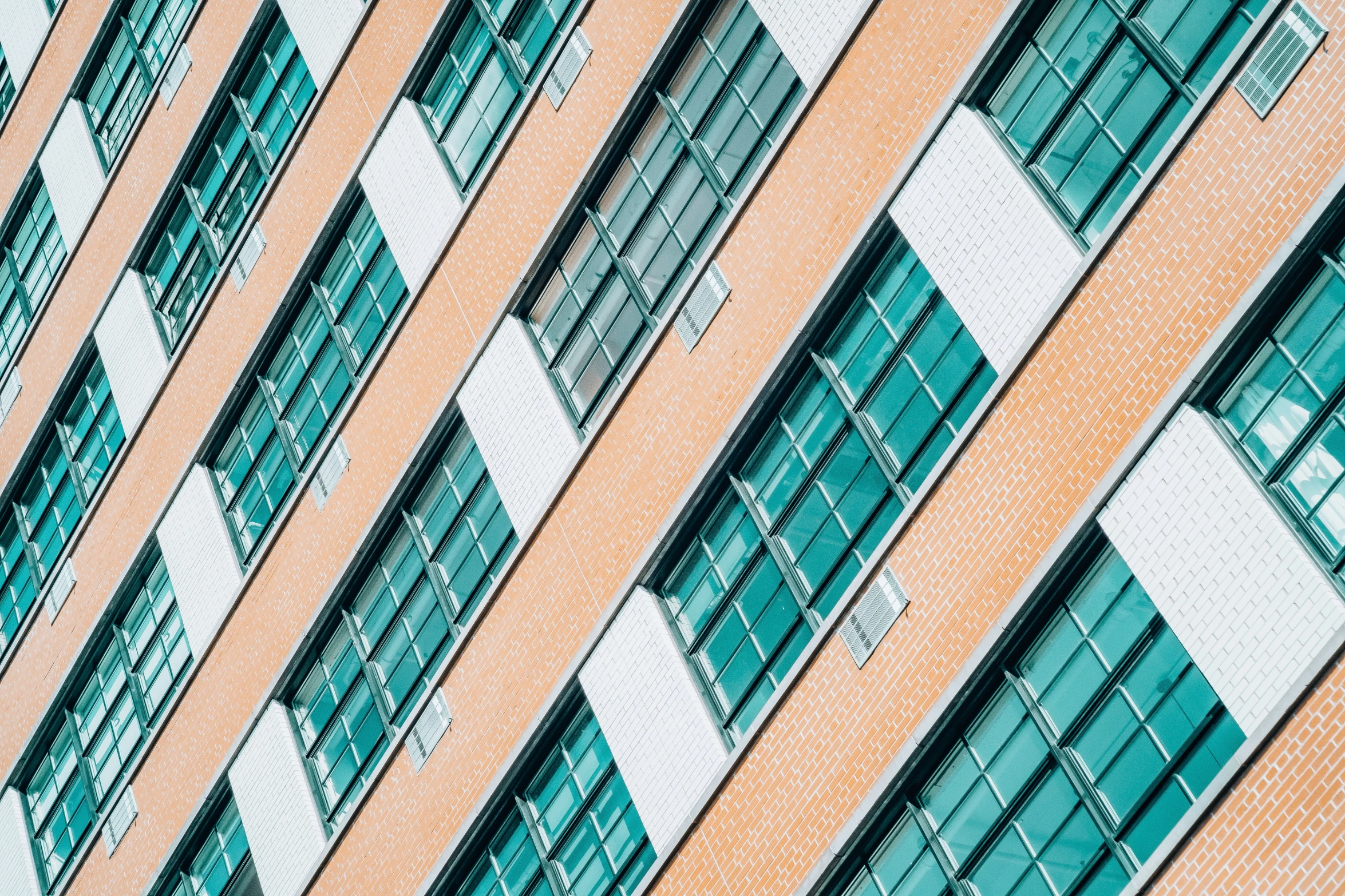 a tall orange building with windows and lots of green windows