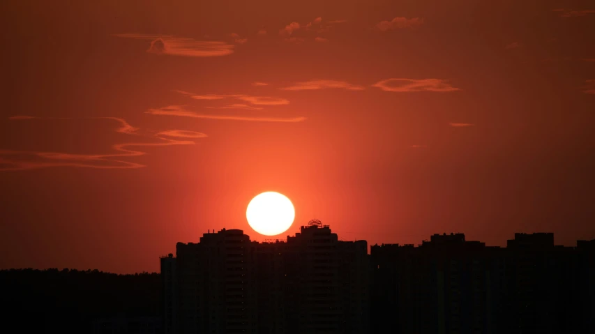 a big yellow ball in the sky above some buildings