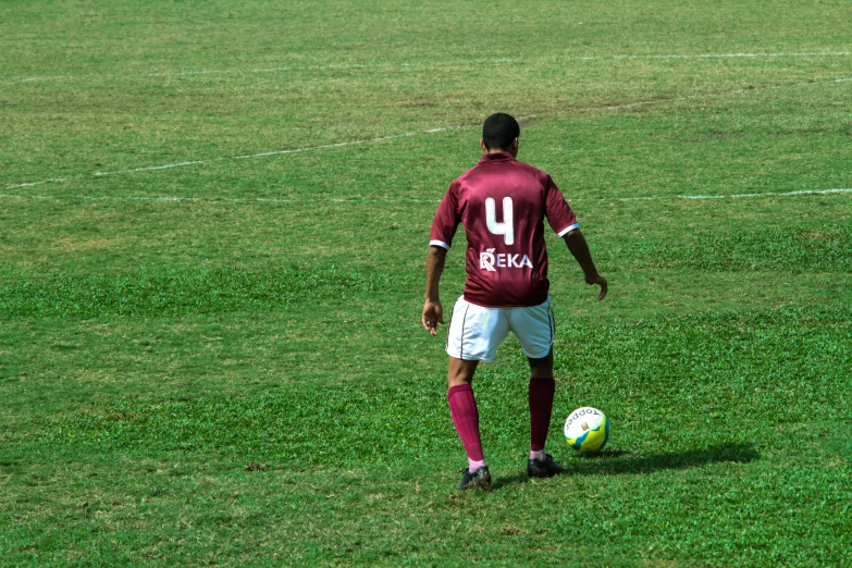 a person in red shirt with soccer ball in grassy field
