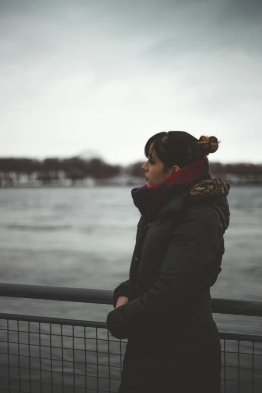 a woman looking over the side of a fence next to the ocean