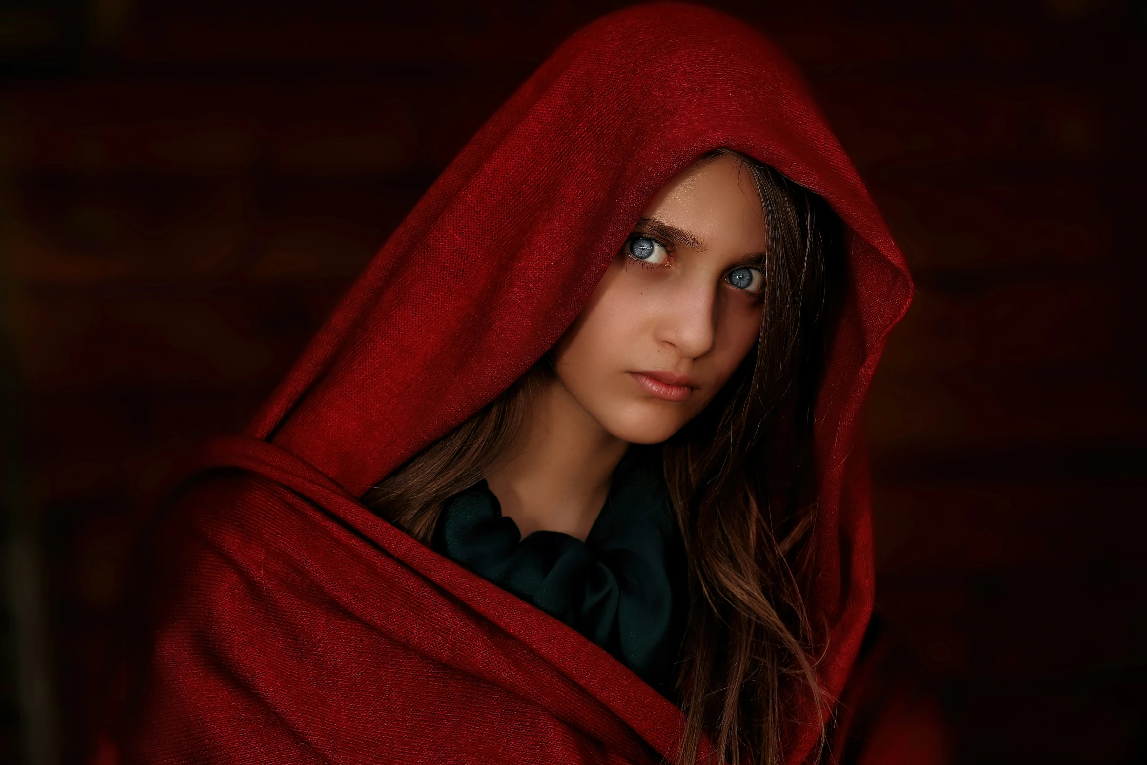 a young woman in a red cape is staring into the camera