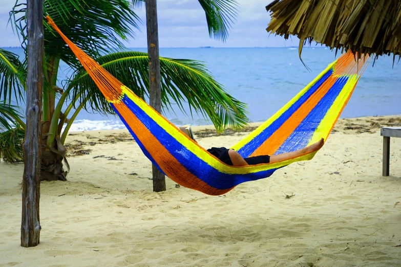 a person relaxing in a colorful hammock at the beach