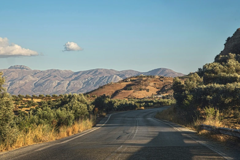 an empty road is winding through a mountainous landscape