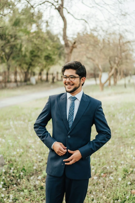 a man in a suit and glasses standing on grass