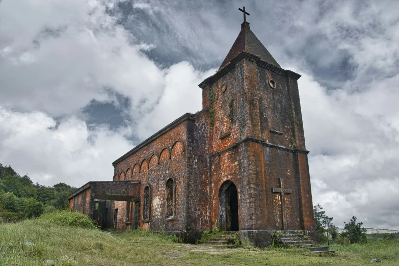 an old church in a grassy area under cloudy skies