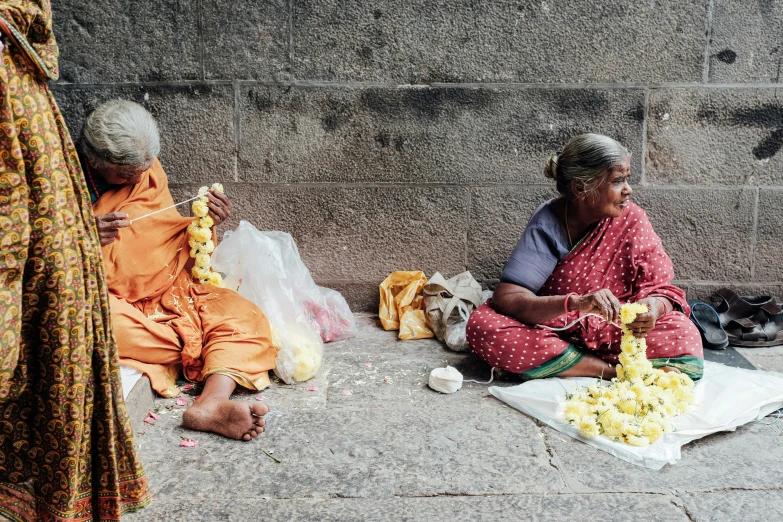 three ladies sitting on the sidewalk and eating