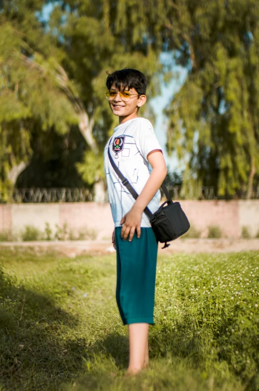 a small boy holding his back while standing in a field