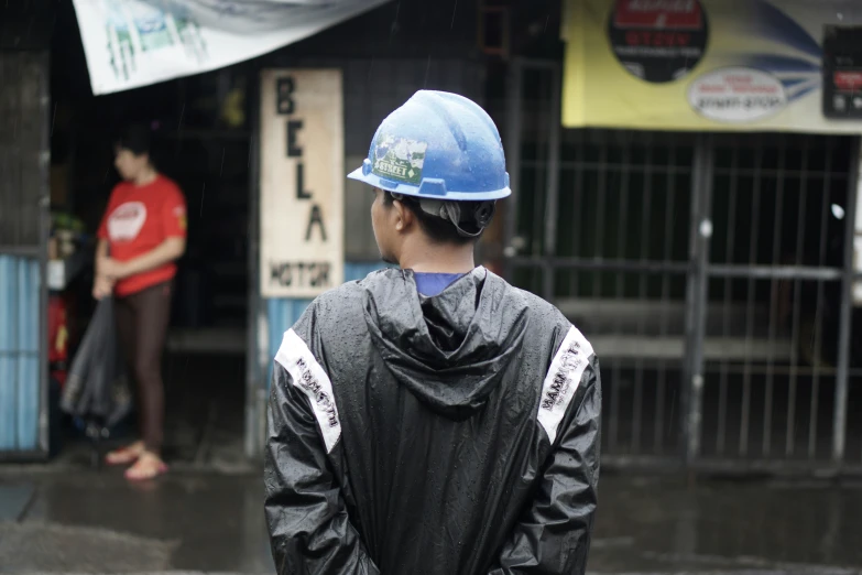 a man wearing a hard hat and rain coat standing in front of a shop