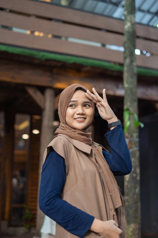 a woman in a brown shawl and blue sleeve shirt is smiling