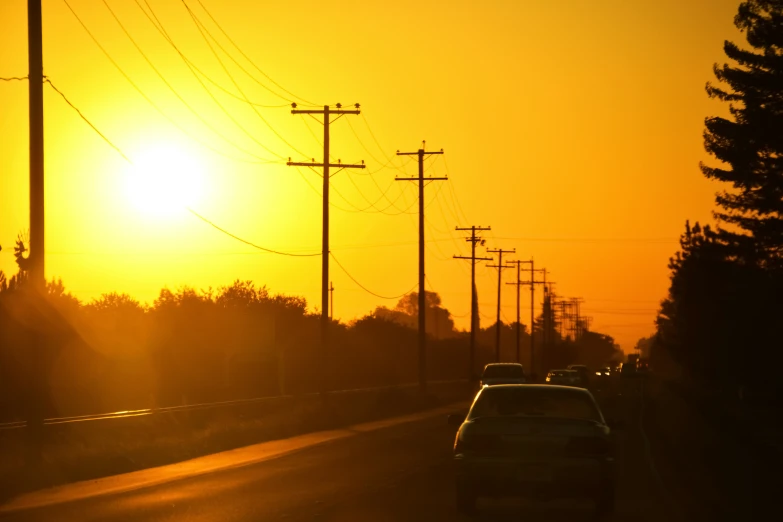 the sun setting behind some telephone poles and power lines