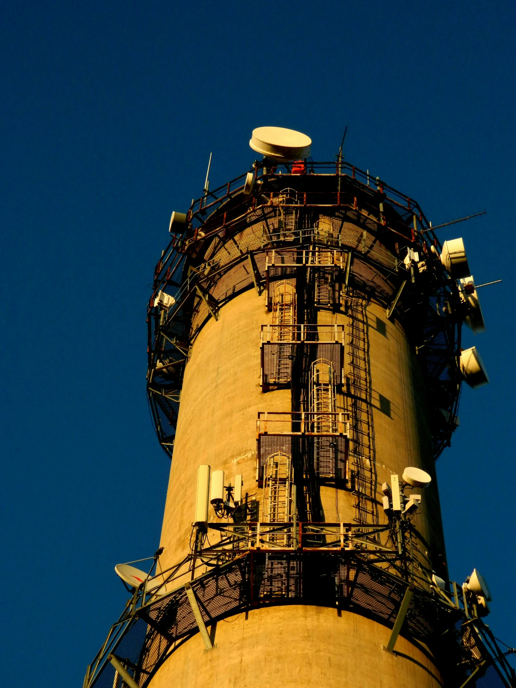 an old rusty, yellow and blue tower is seen with multiple wires on the sides