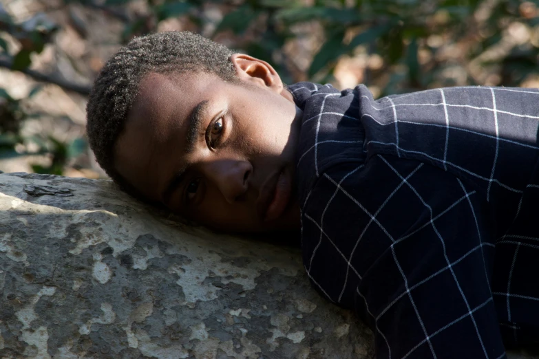 the young man is laying down on a large rock