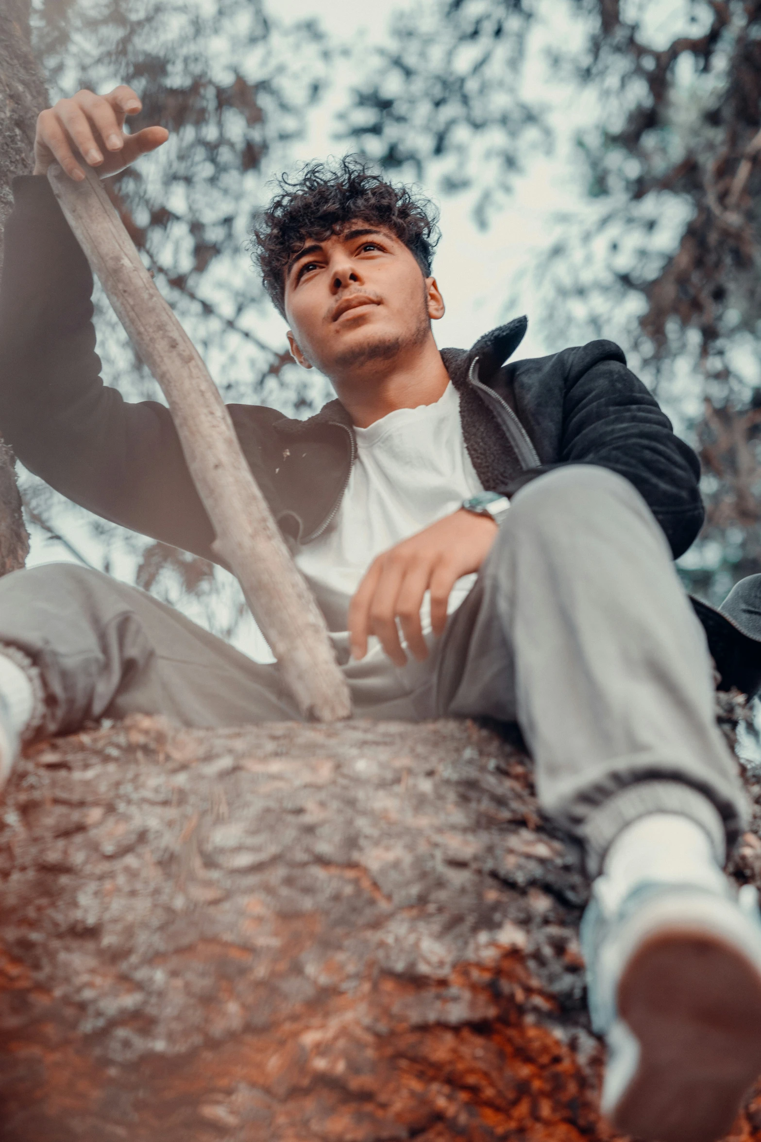 a young man sitting on a fallen tree