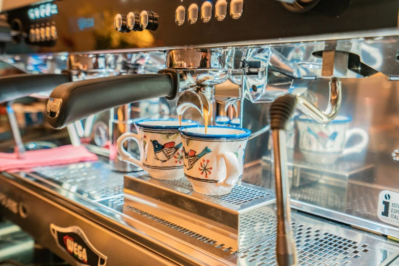 two coffee mugs are being hed into the espresso machine