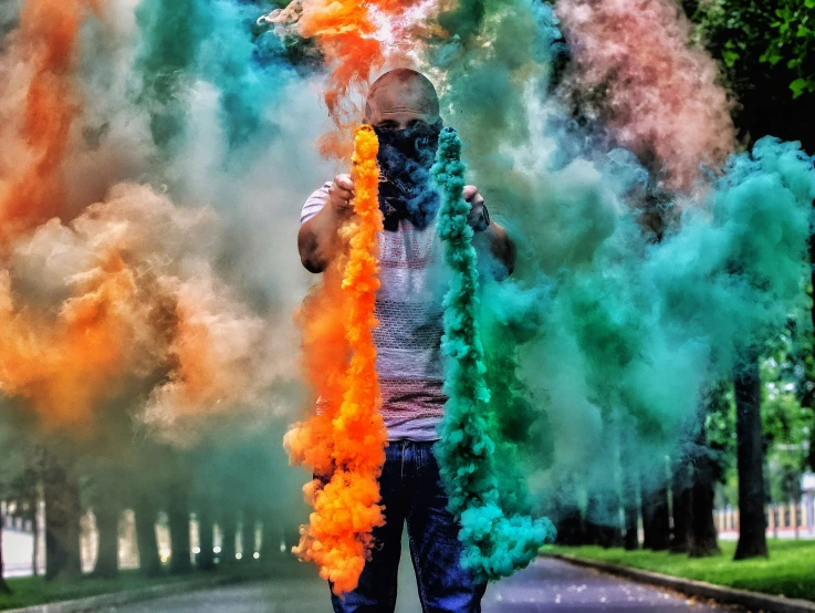 a person standing on a street holding up orange and blue smoke