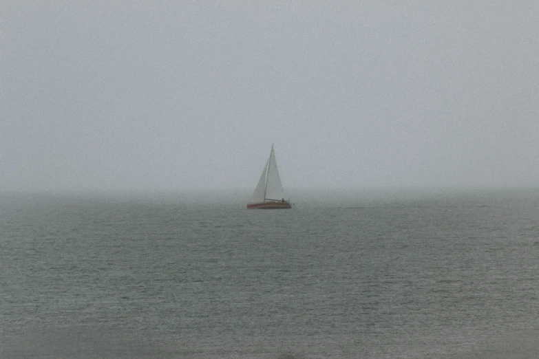 a boat floating across the ocean on a very foggy day